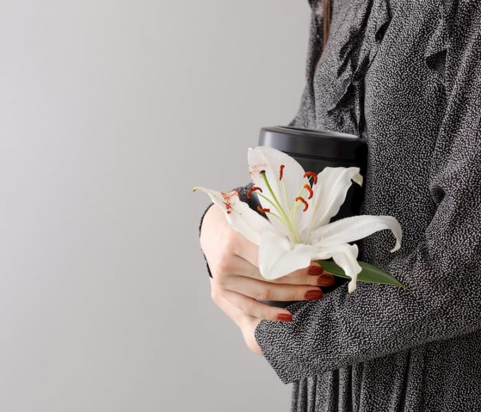 woman in grey coat holding a white lily
