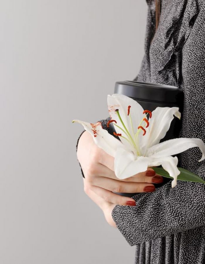 woman in grey coat holding a white lily woman in grey coat holding a white lily